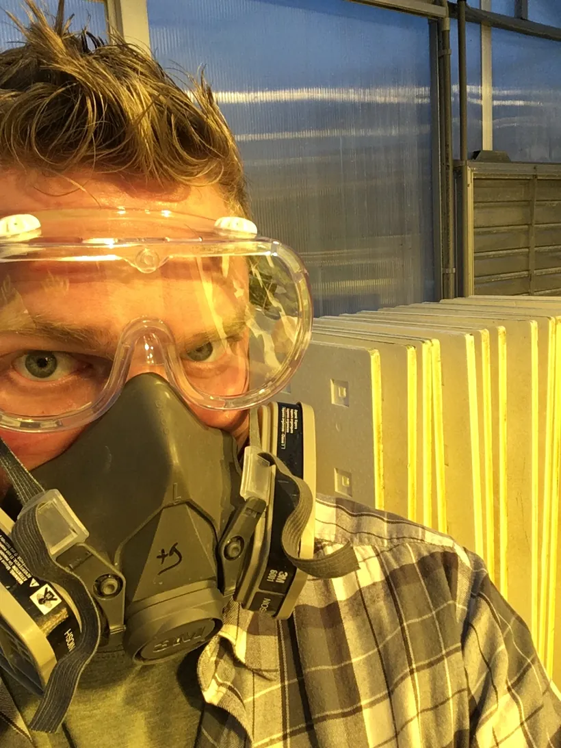 Sean Fogarty in a respirator and safety goggles, sanitizing equipment in a controlled-environment greenhouse.